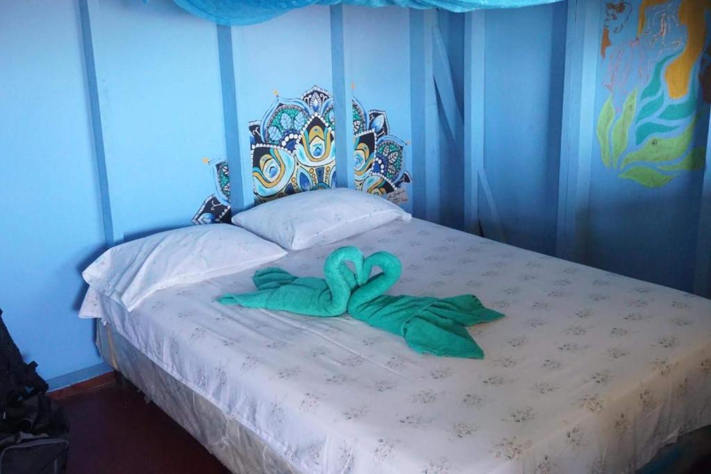 Schlafzimmer mit einem Bett mit blauem Kopfteil und einem grünen Band in der Unterkunft Cool Spot Grace Place in Little Corn Island