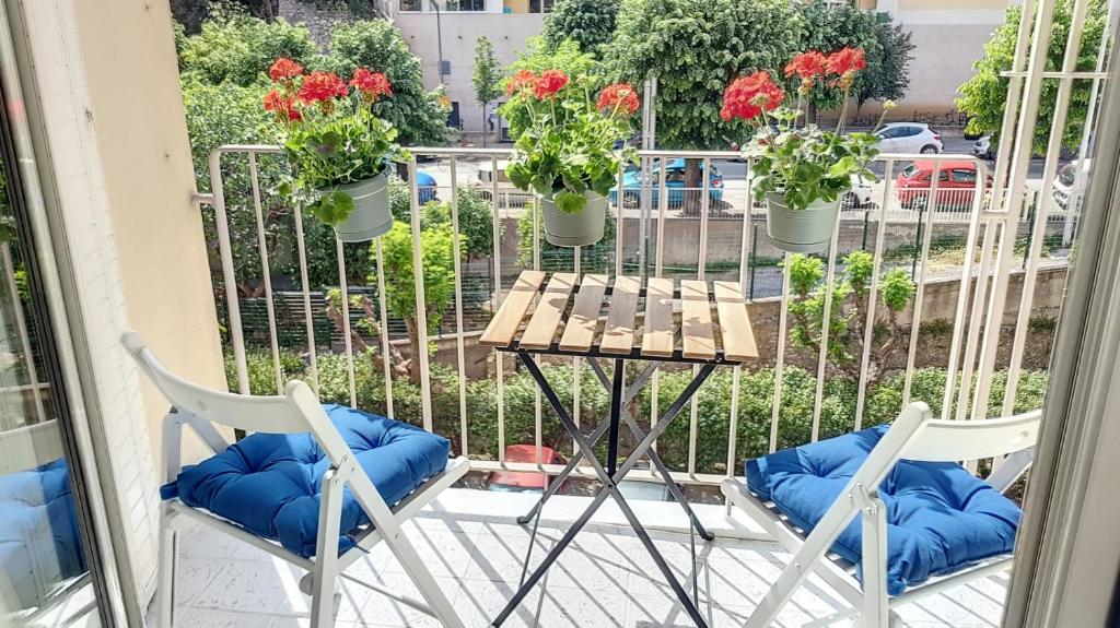 two chairs and a table on a balcony with flowers at Superbe appartement style architecte/unique** in Nice