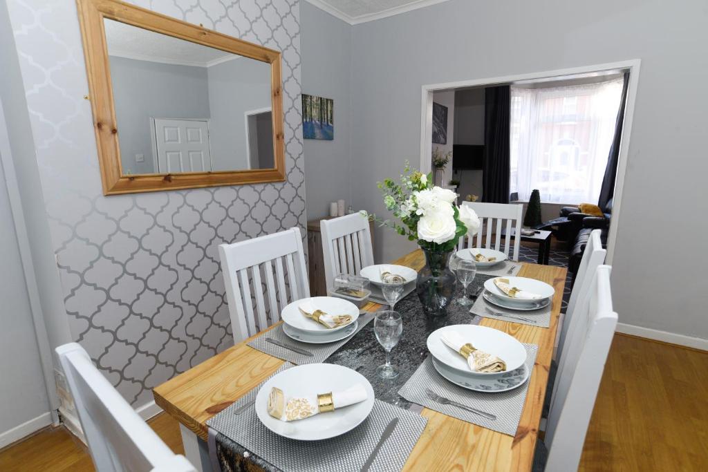 una sala da pranzo con tavolo, sedie e specchio di Minshull House a Crewe
