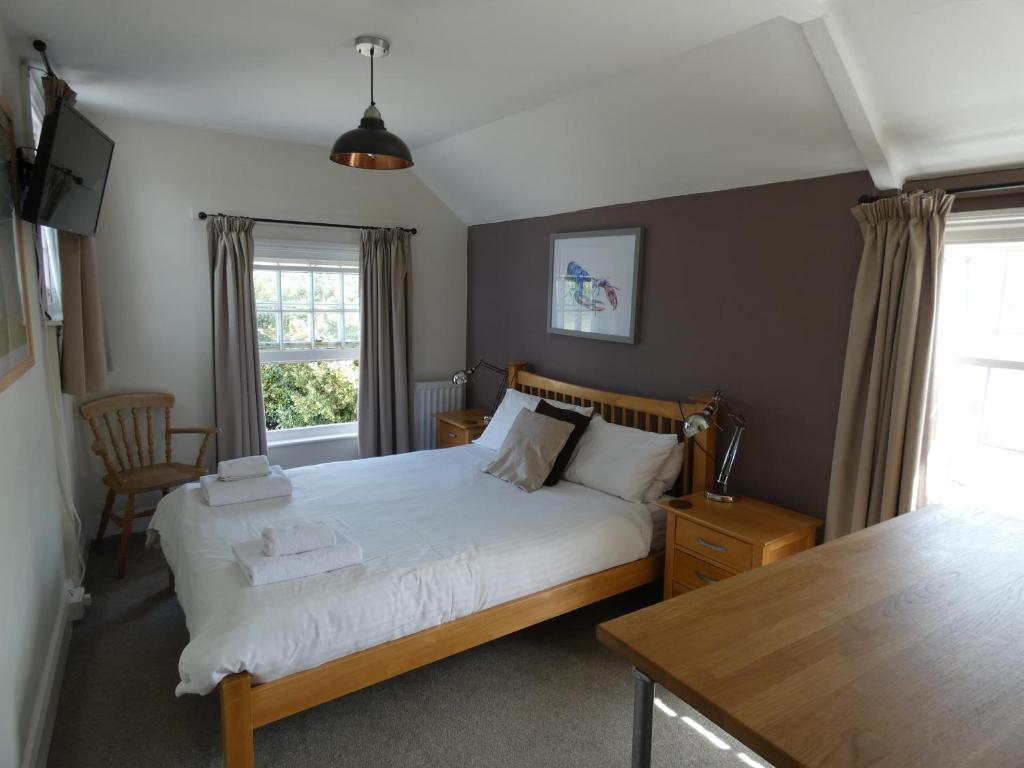 1 dormitorio con cama, mesa y ventana en The Sloop Inn en Kingsbridge