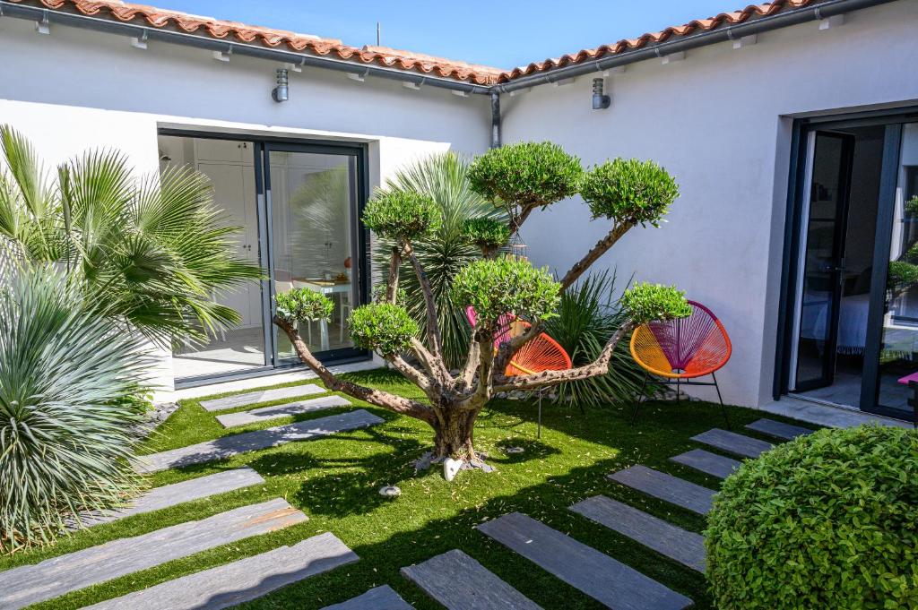 un giardino con un albero al centro di una casa di Le Clos des Fantaisies a Rivedoux-Plage