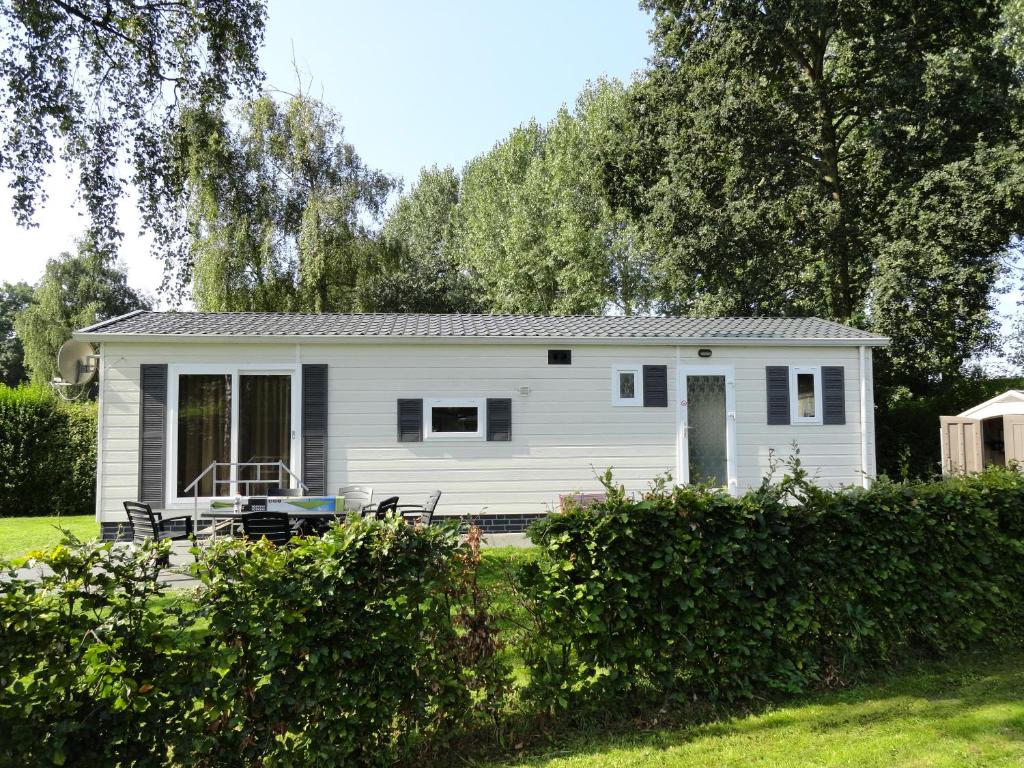 une petite maison blanche au milieu d'une cour dans l'établissement Stellechalets op Vakantiepark Stelleplas - Heinkenszand, à Heinkensand