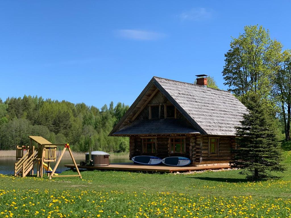 een blokhut met een terras naast een meer bij Vucini in Andzeļi