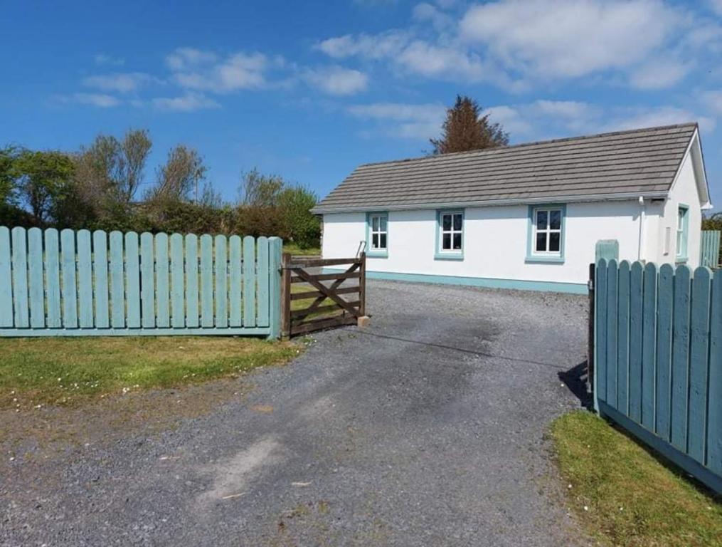 a white house with a fence and a gate at Lislary Cottage on Wild Atlantic Way in Sligo