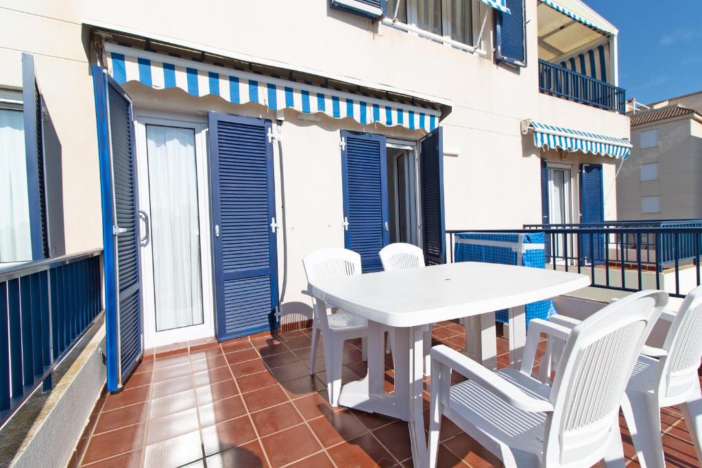 balcón con mesa blanca y sillas blancas en Global Properties, Precioso apartamento con terraza y vistas al mar, en Canet de Berenguer