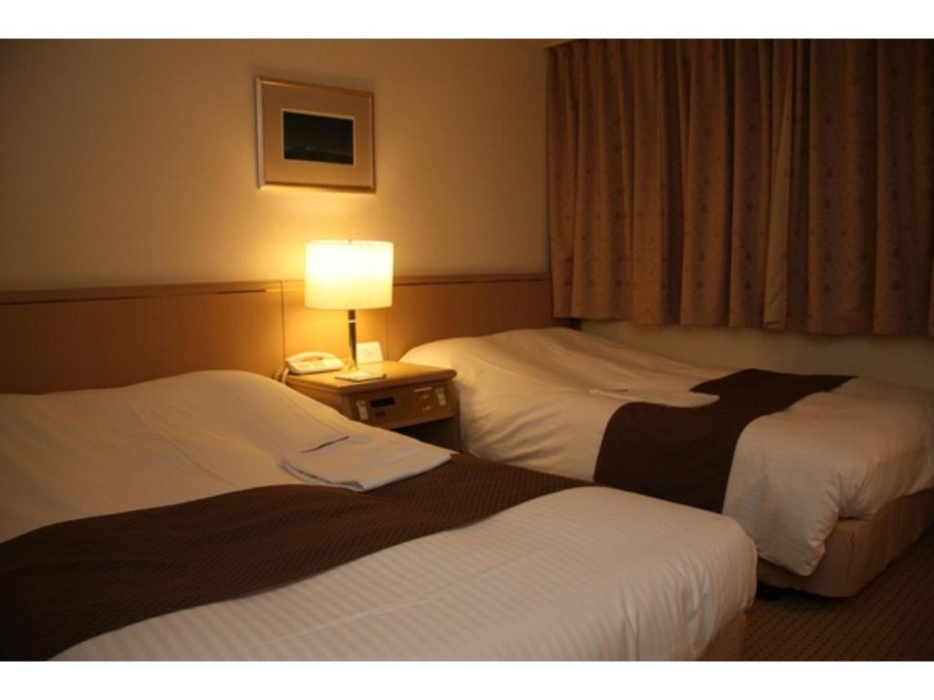 2 Betten in einem Hotelzimmer mit einer Lampe auf einem Tisch in der Unterkunft Kitami Pierson Hotel - Vacation STAY 54806v in Kitami