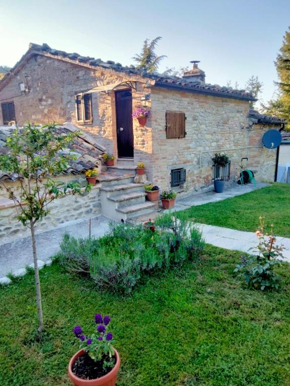 una casa de piedra con un jardín delante de ella en Il giardino dei sogni, en Montefortino