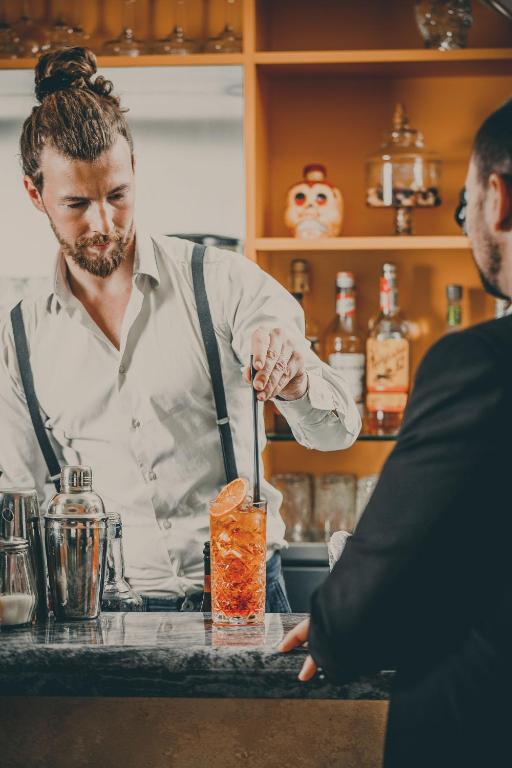 a man standing at a bar making a drink at Hotel Albatros Varigotti in Varigotti