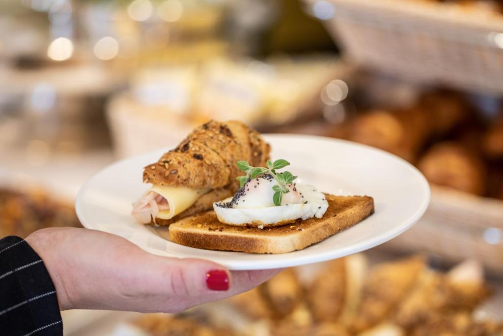 a person holding a white plate with a sandwich at Hotel Albatros Varigotti in Varigotti