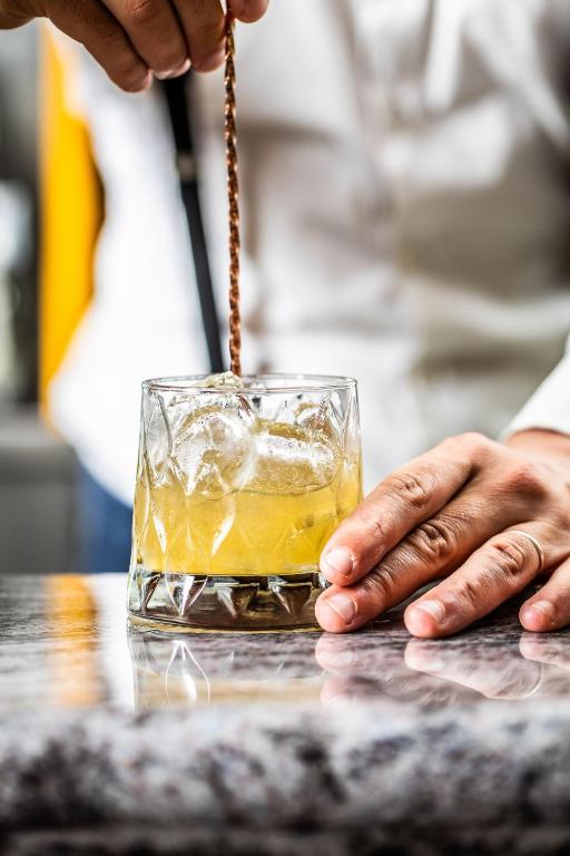 a person is stirring a drink in a glass at Hotel Albatros Varigotti in Varigotti