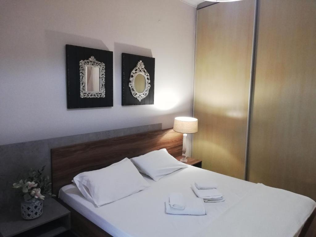 ein Schlafzimmer mit einem weißen Bett mit zwei Spiegeln an der Wand in der Unterkunft NICOL APARTMENS in Preveza