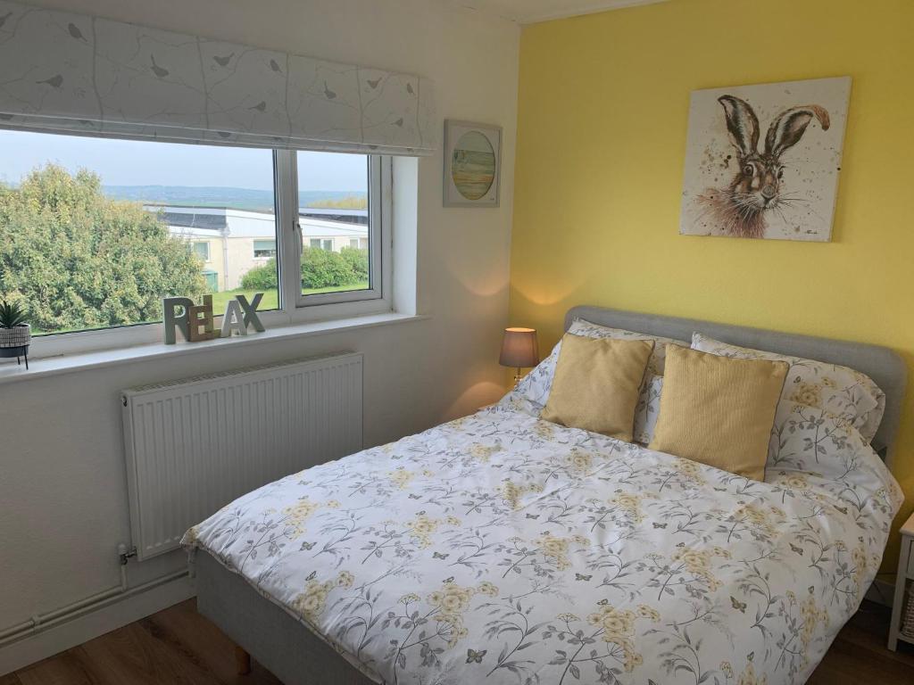 a bedroom with a bed and a window at Chalet 26 Widemouth Bay in Bude