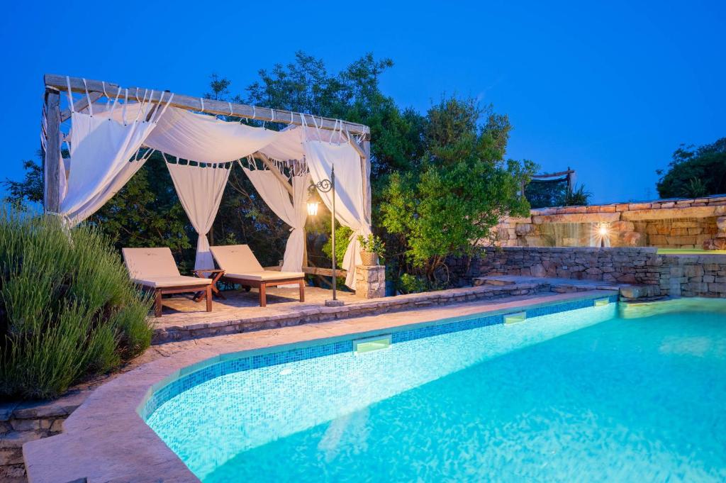 a swimming pool with two chairs and a gazebo at Nono Ban Hotel & Villa in Gornji Humac