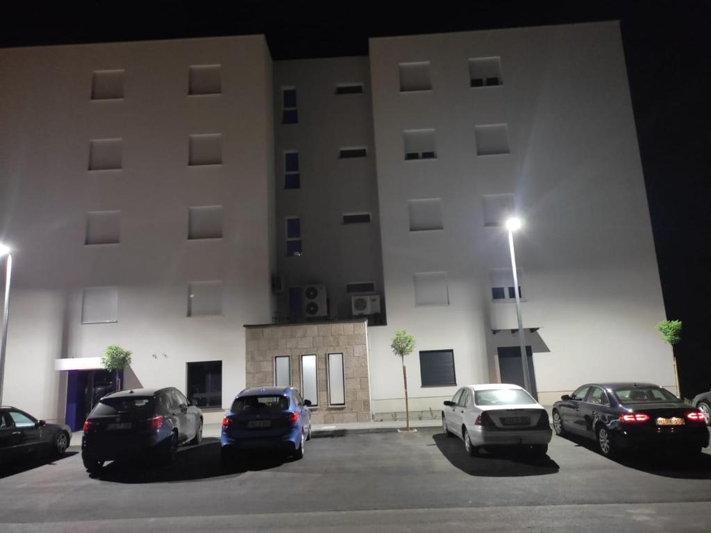 a large building with cars parked in a parking lot at Apartman San in Posušje