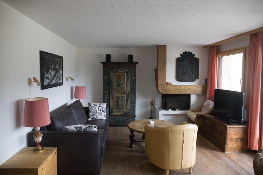 a living room with a couch and a tv at Chesa Mutaun in Silvaplana