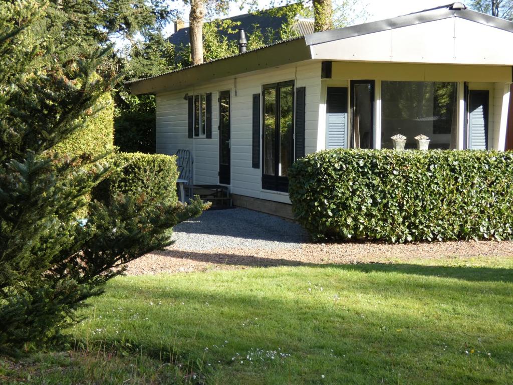 a small white house with a grass yard at Chalet nr 10 op Bospark Trimunt in Marum