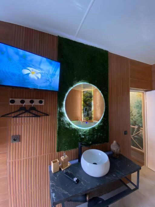 W łazience znajduje się okrągłe lustro i umywalka. w obiekcie Esprit BALI ....LOVE SPA, Sauna de luxe à Mulhouse w Miluzie