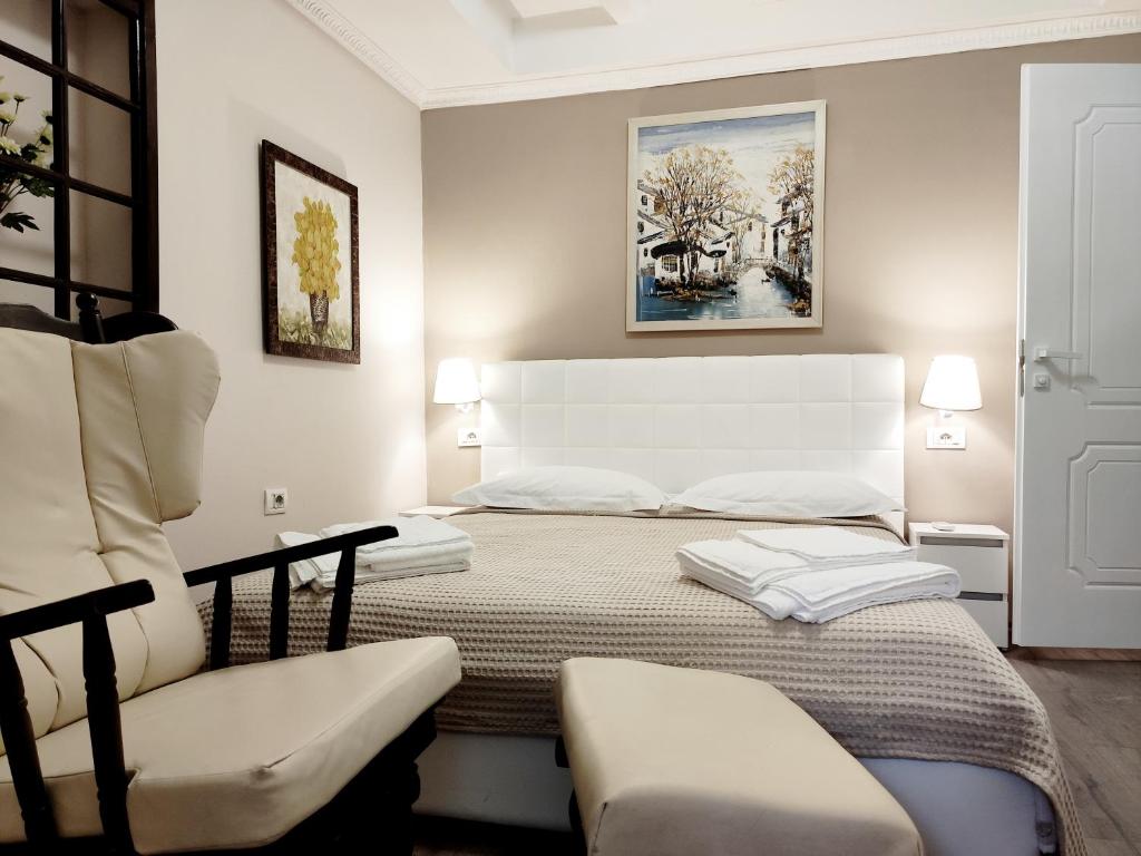ein weißes Schlafzimmer mit einem Bett und einem Stuhl in der Unterkunft Tanners' Bridge Apartments in Tirana