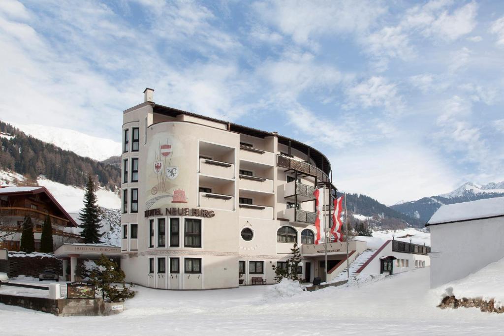 un edificio nella neve con montagne sullo sfondo di Hotel Neue Burg a Nauders