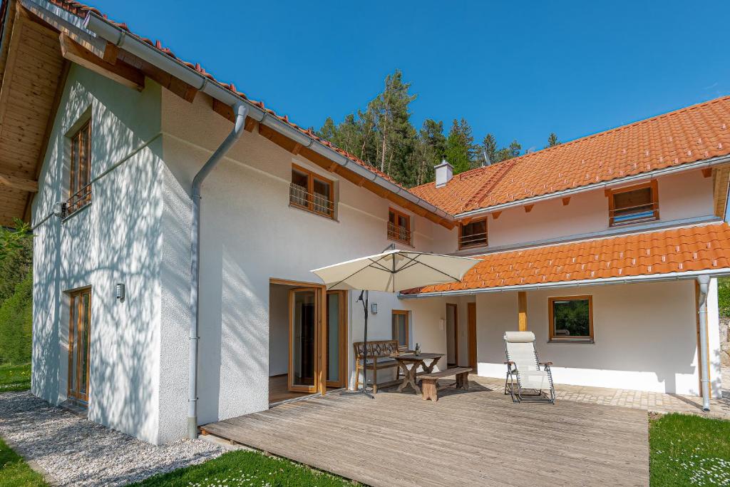 eine Terrasse eines Hauses mit einem Tisch und einem Sonnenschirm in der Unterkunft Ferienhaus Schlierachtal in Miesbach
