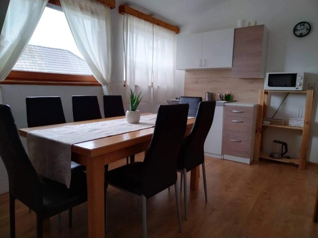 a dining room table with black chairs and a kitchen at Apartment Mila in Plitvička Jezera