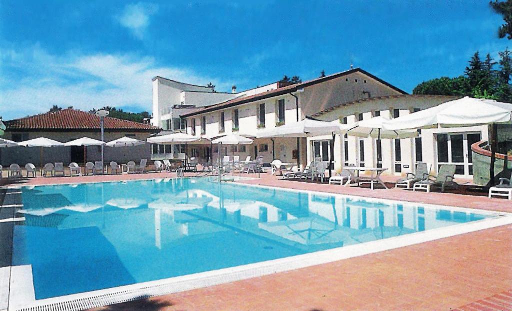 a swimming pool with chairs and umbrellas next to a building at I Girasoli in Lucignano
