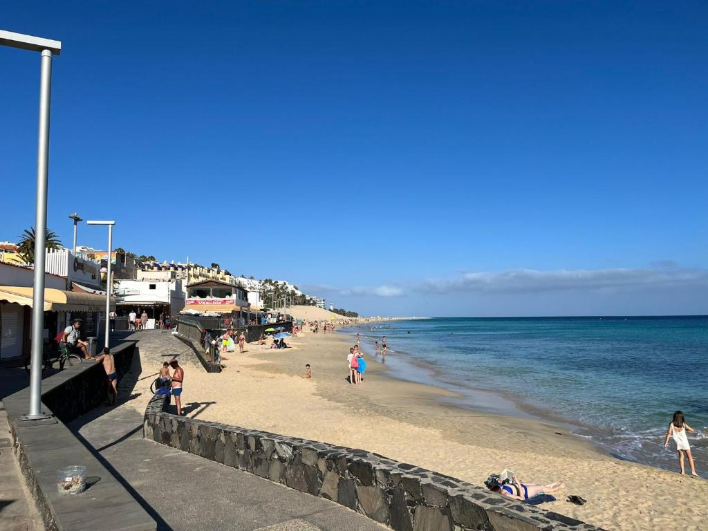 un groupe de personnes sur une plage près de l'océan dans l'établissement Heva Home, à Tarajalejo