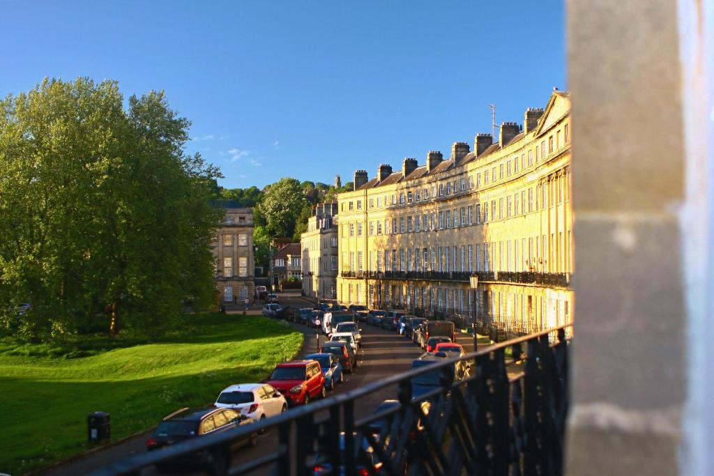 巴斯的住宿－A Rare Georgian Crescent Residence with parking，停在建筑物旁边的街道上的一排汽车