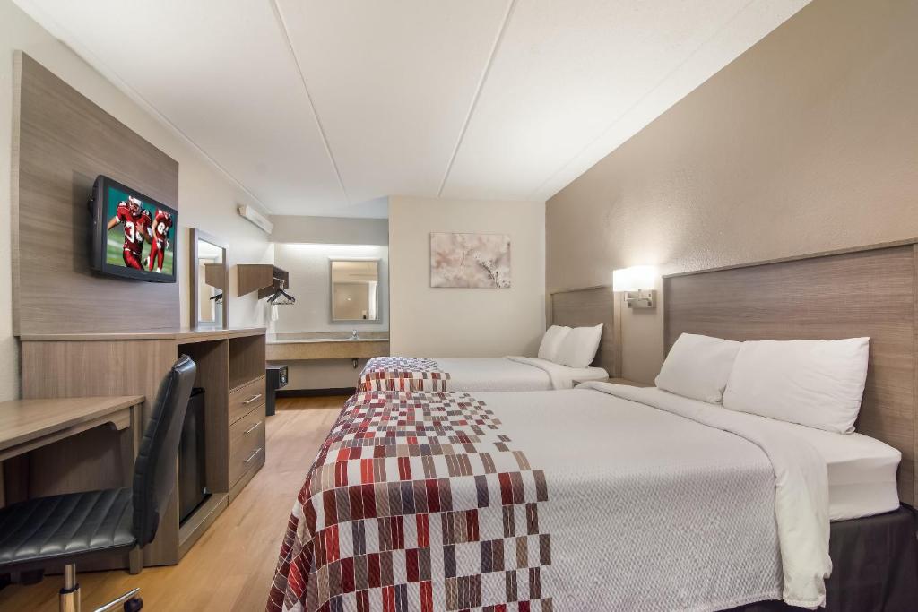um quarto de hotel com duas camas e uma televisão em Red Roof Inn Durham - Triangle Park em Durham