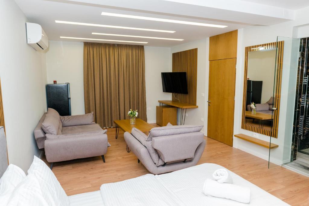 uma sala de estar com duas cadeiras e uma televisão em Hotel Pazari & Apartments em Korçë
