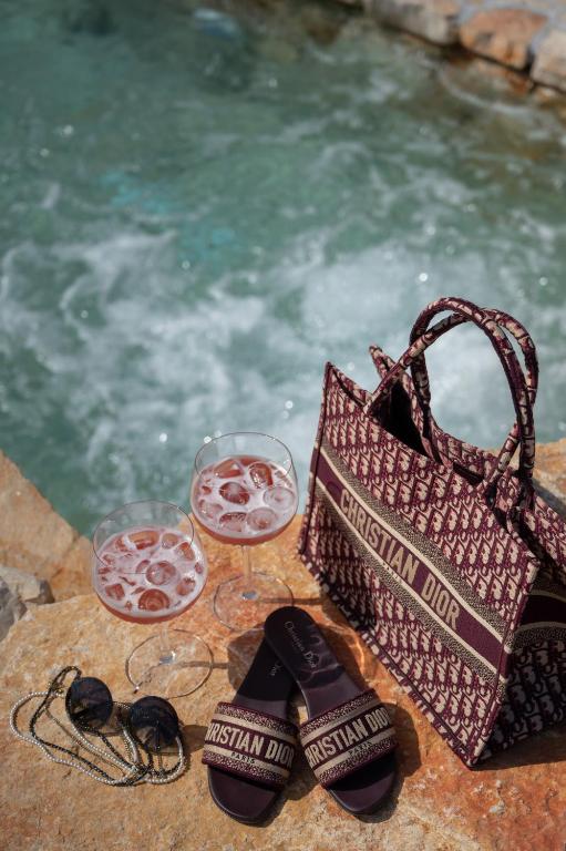 a table with two glasses of wine and a purse and glasses of wine glasses at Nono Ban Hotel & Villa in Gornji Humac