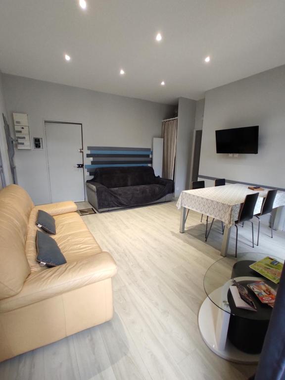 ein Wohnzimmer mit einem Sofa und einem Tisch in der Unterkunft Agréable T2 au centre de Luchon in Luchon