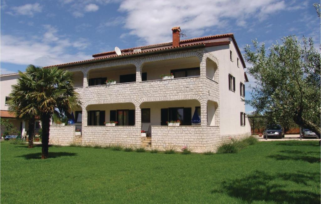 a white brick house with a palm tree in front of it at Pet Friendly Apartment In Porec With Wifi in Poreč