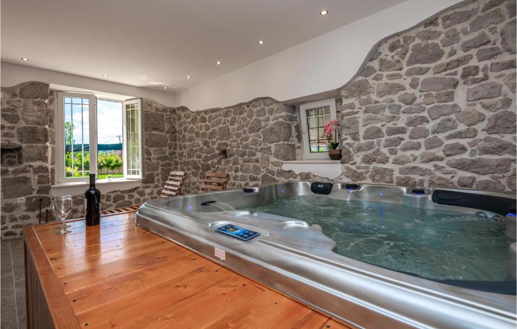 a hot tub in a room with a stone wall at Awesome Home In Vinjani Donji With 5 Bedrooms, Wifi And Outdoor Swimming Pool in Bilopavlovići