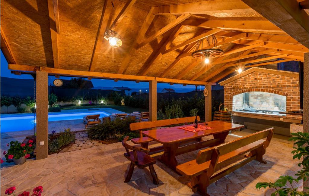 a patio with a table and benches and a pool at Awesome Home In Vinjani Donji With 5 Bedrooms, Wifi And Outdoor Swimming Pool in Bilopavlovići