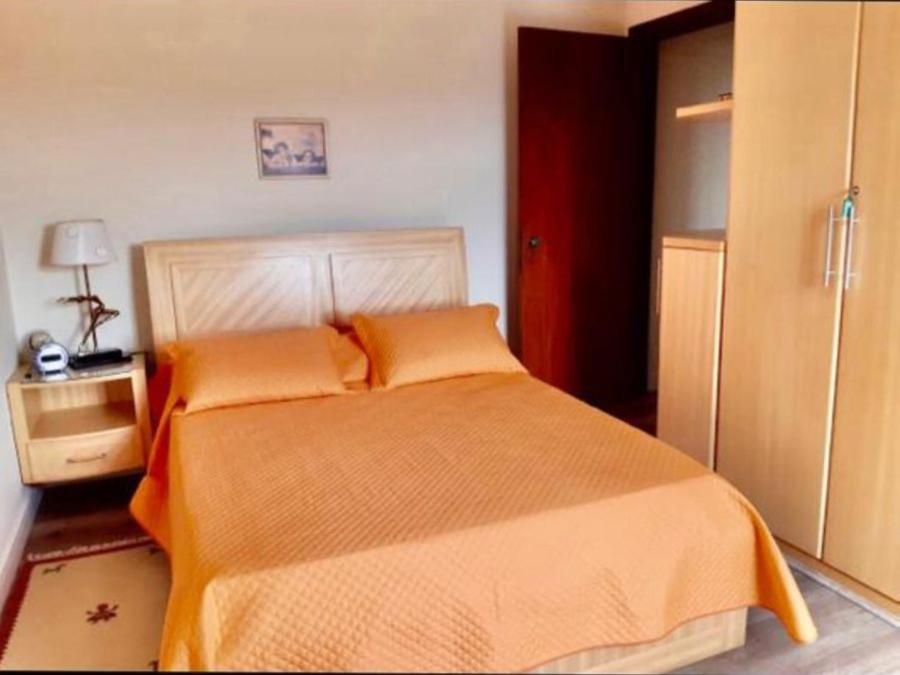 a bedroom with a large bed with an orange blanket at Piemonte Flat Serra Negra in Serra Negra