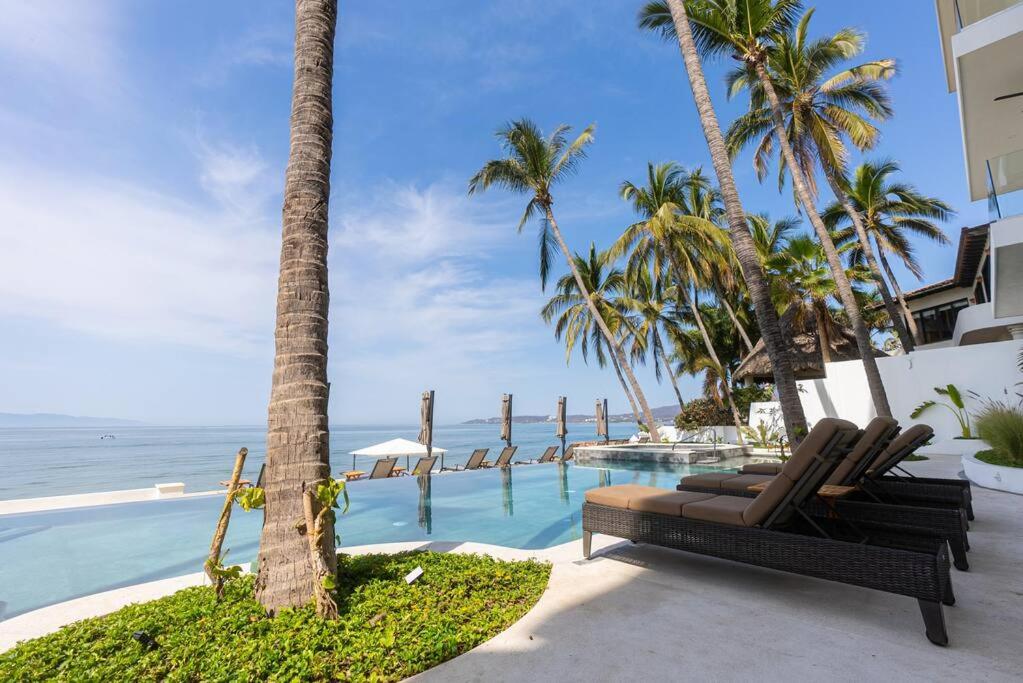 a pool with chairs and palm trees next to the ocean at Nayri Ocean 401 in Bucerías
