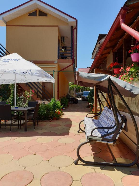 um pátio com uma cadeira, um guarda-chuva e uma mesa em Casa Mary em Costinesti