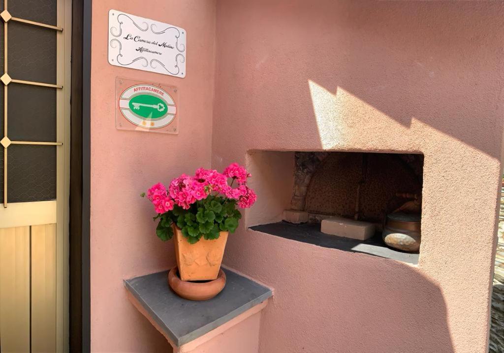 a pink house with a flower pot on a shelf at La camera del mulino in Levanto
