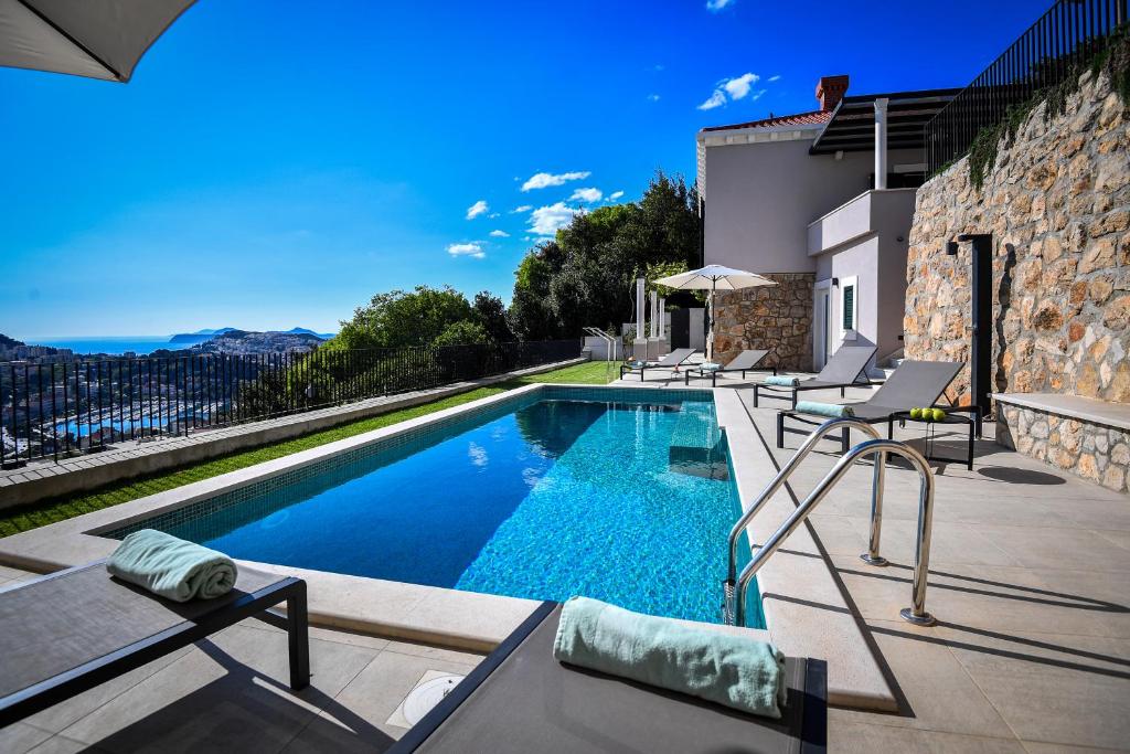 a swimming pool with chairs and a house at Villa Oranž in Dubrovnik