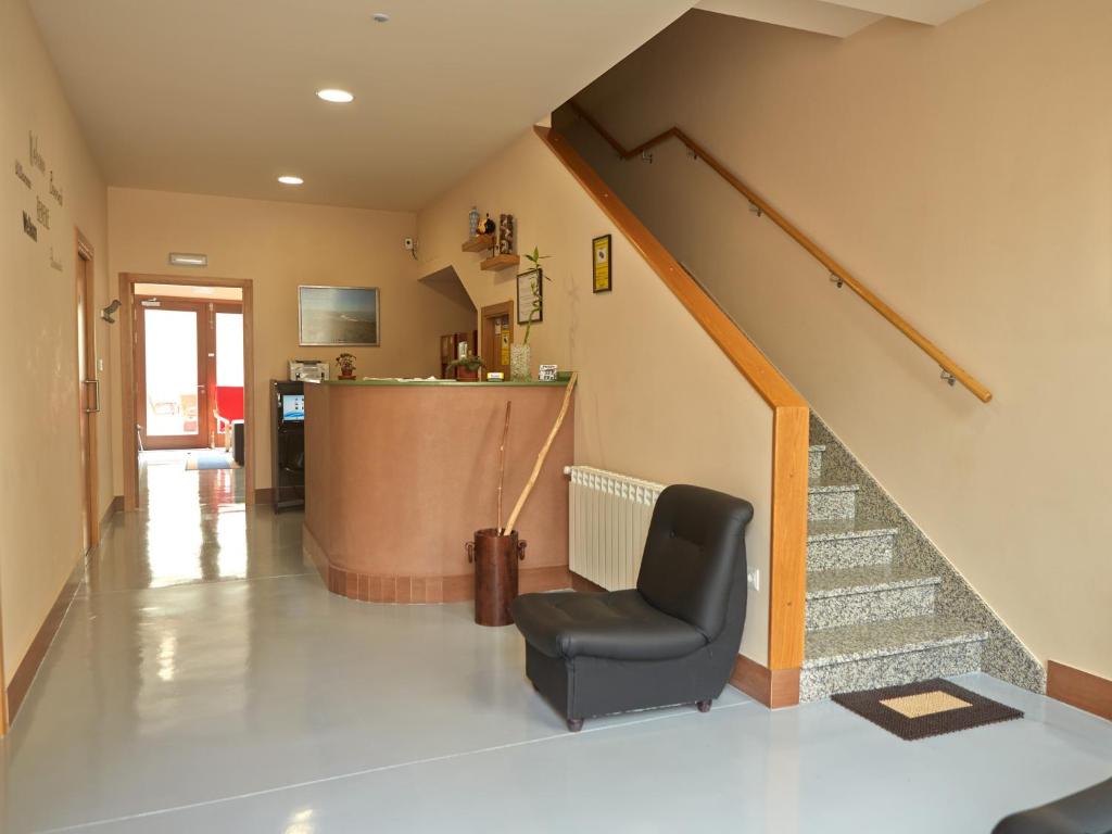 a living room with a chair and a staircase at Albergue Pereiro in Melide