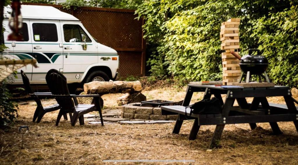a picnic table and chairs in a backyard with a grill at Van Camping - Do Something Different! in Landrum