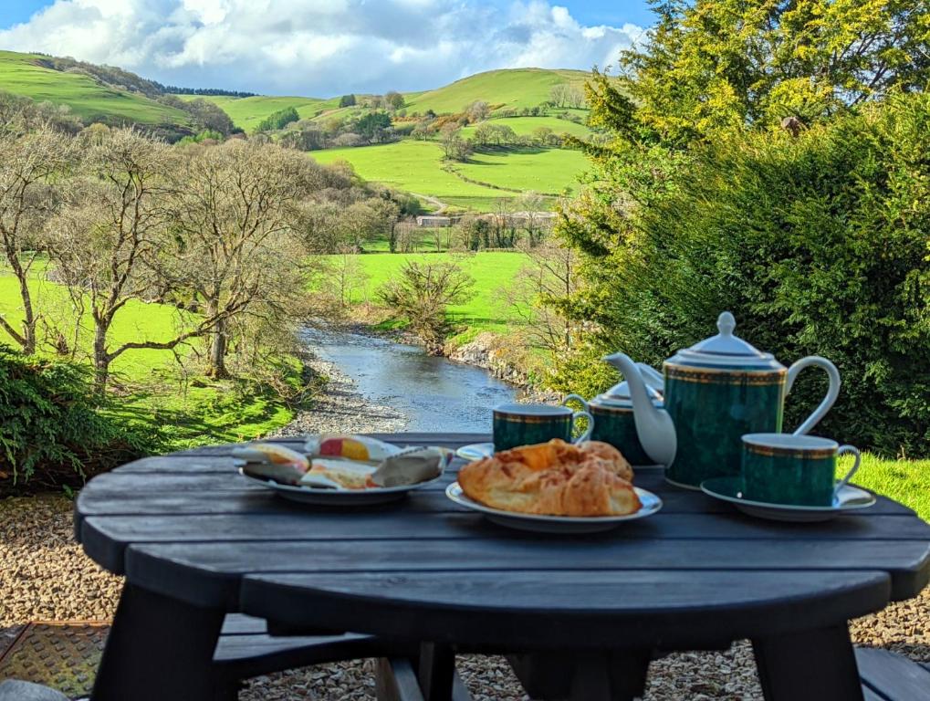 un tavolo con piatti di cibo e tazze e un fiume di Aberhiriaeth Hall - Country House By River Dyfi a Cemmaes