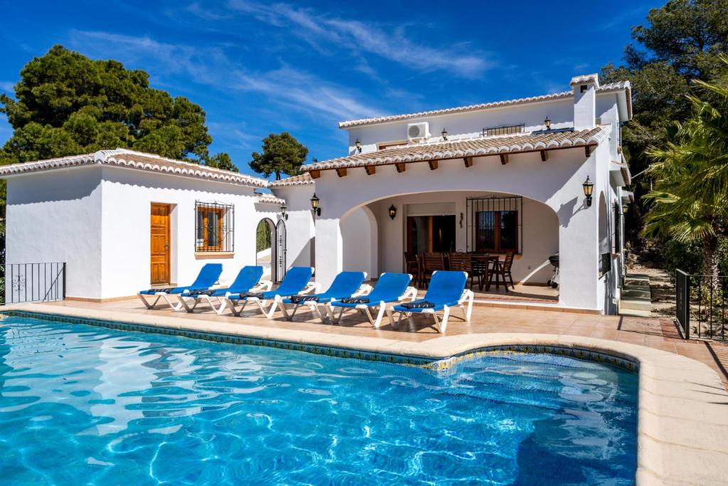 a villa with a swimming pool and blue chairs at Carpe Diem in Jávea