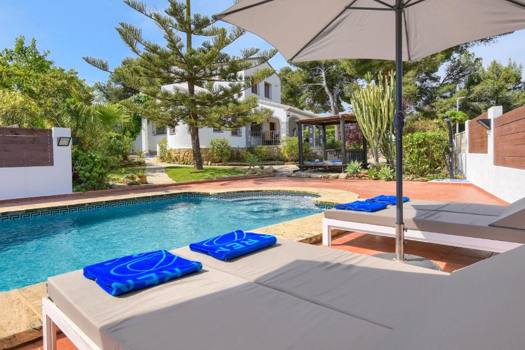 een zwembad met 2 ligstoelen en een parasol bij Villa Luna in Jávea