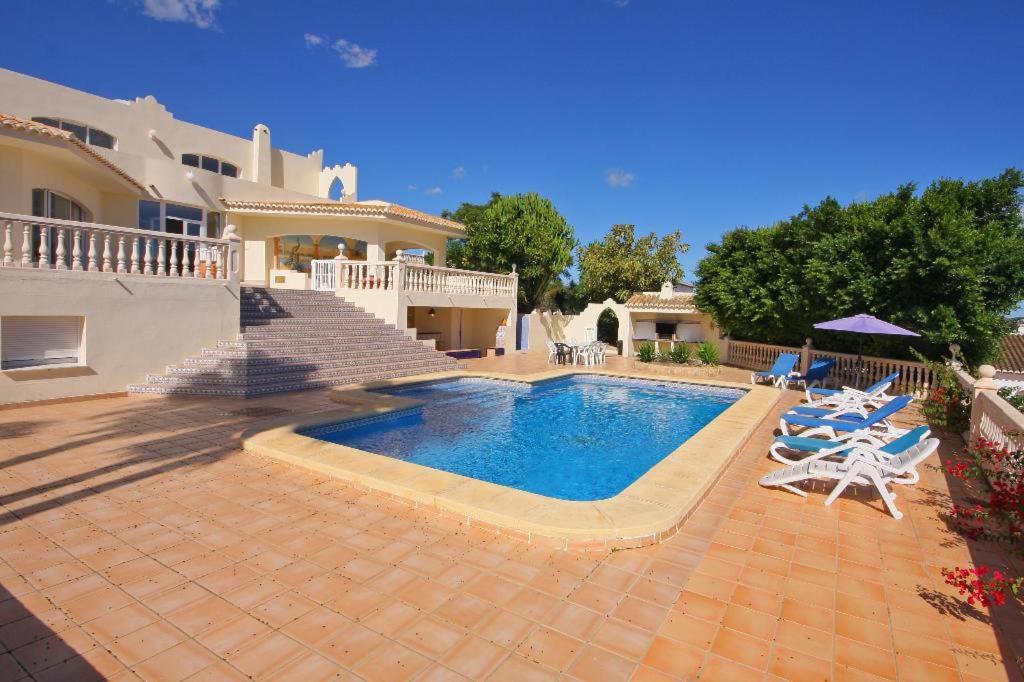 a villa with a swimming pool in front of a house at Villa Cora in Jávea