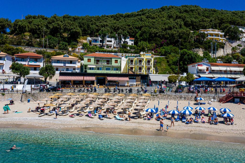 a group of people on a beach with chairs and umbrellas at Olympia House in Parga