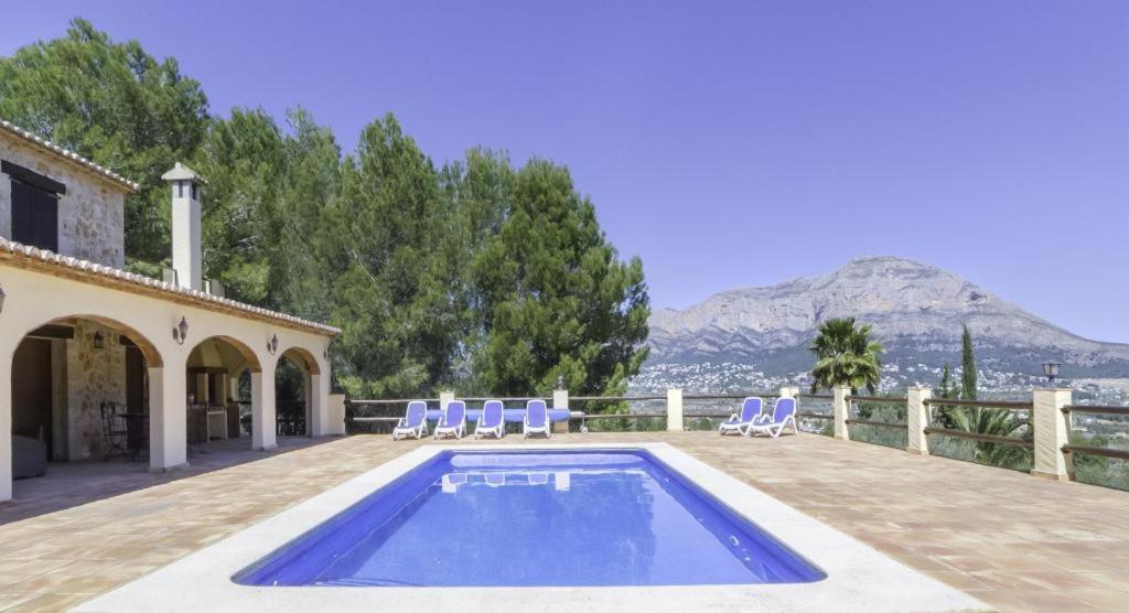 a swimming pool with chairs and a house at Pura Vida in Jávea