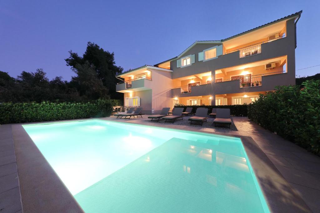 a house with a swimming pool in front of a building at Apartments BoBo in Kraj