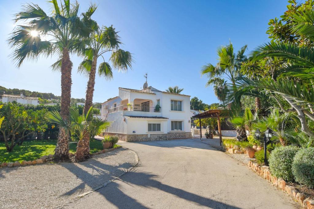Una casa con palmeras y una entrada para coches. en Andrago, en Moraira